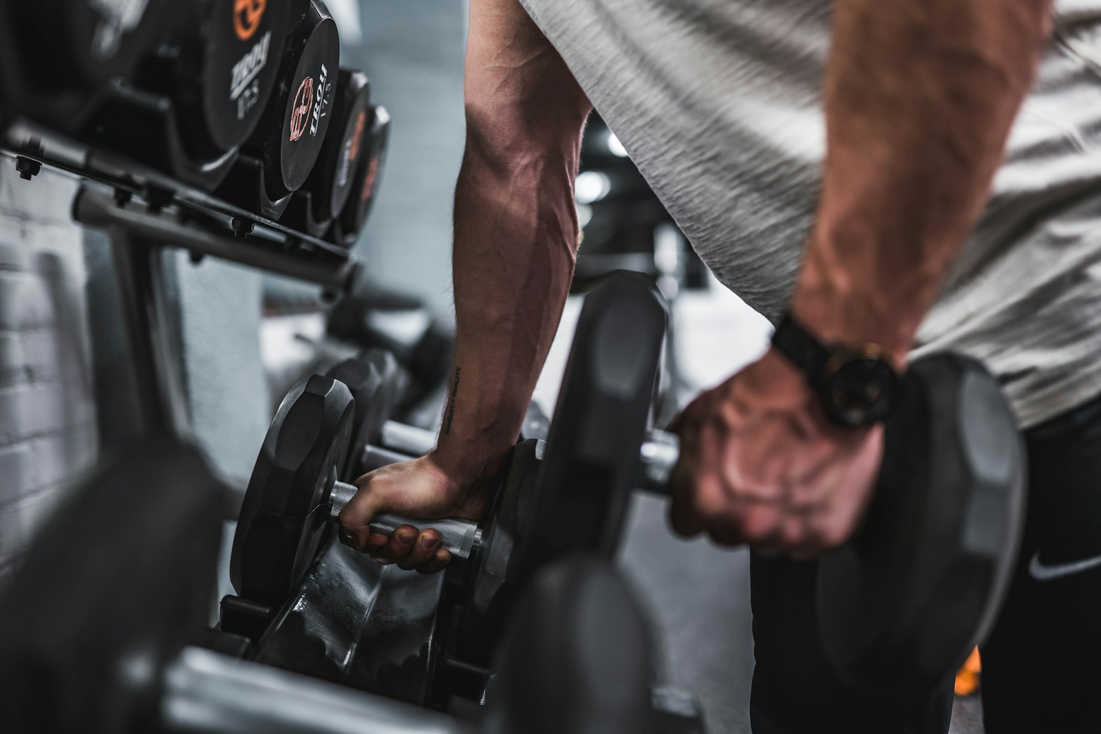 Person lifting a dumbbell from a rack in a gym